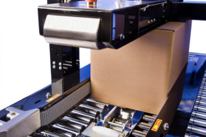 A cardboard box goes through case sealing equipment